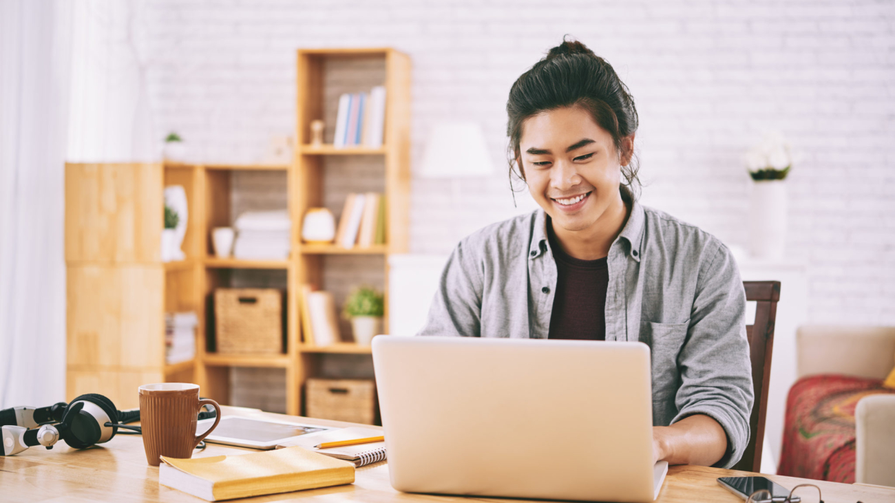 Handsome creative young Vietnamese man working on laptop at his table